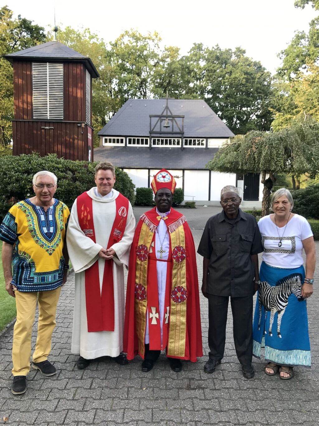 Jacoba und Walter Schulz (außen) zusammen mit dem lutherischen Bischof Amon Kinyunyu und dem muslimischen Bürgermeister Mohamed Mayingu sowie Pastor Thorsten Jacobs 2019 vor der Pauluskirche in Dalum.